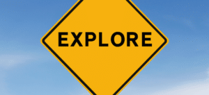 A yellow diamond-shaped road sign with the word 'Explore' against a clear blue sky, symbolizing the journey of discovery.