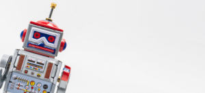 A minimalist close-up of a retro-style robot on a clean white background. The robot has red and blue accents, evoking a sense of simplicity and technology.