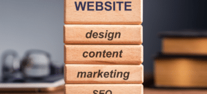 Close-up photo of stacked wooden blocks labeled website, design, content, marketing, and SEO, visually representing the building blocks of a full stack marketing strategy.
