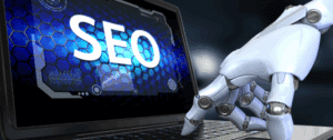 Close-up of a robotic hand typing on a laptop keyboard displaying the word 'SEO' on a futuristic blue digital interface, symbolizing artificial intelligence transforming search engine optimization.