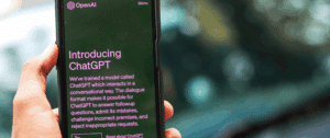 Photo of a hand holding a smartphone with the OpenAI ChatGPT app open, displaying the text 'Introducing ChatGPT' on the screen, with a blurred background.