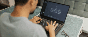 Photo of a person using a laptop with the ChatGPT interface displayed on the screen, shot from behind at a modern desk, highlighting real-world usage of conversational AI technology.