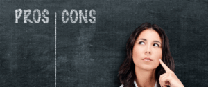 A thoughtful businesswoman stands in front of a chalkboard with “Pros” and “Cons” columns, representing the process of weighing the advantages and disadvantages of in-app advertising on AdWords.
