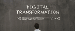 A person stands in front of a chalkboard with the words “DIGITAL TRANSFORMATION” and a progress bar drawn in chalk, representing the shift to AI-powered conversational advertising in digital marketing.