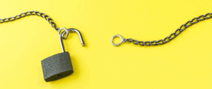 A close-up of a broken metal chain with an unlocked padlock on a bright yellow background, representing the concept of unlocking new opportunities for brand visibility in AI-powered search tools.