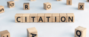 Wooden letter blocks arranged to spell “CITATION” on a light surface, with scattered blocks in the background, representing the concept of managing and organizing business citations for local SEO and store visibility.