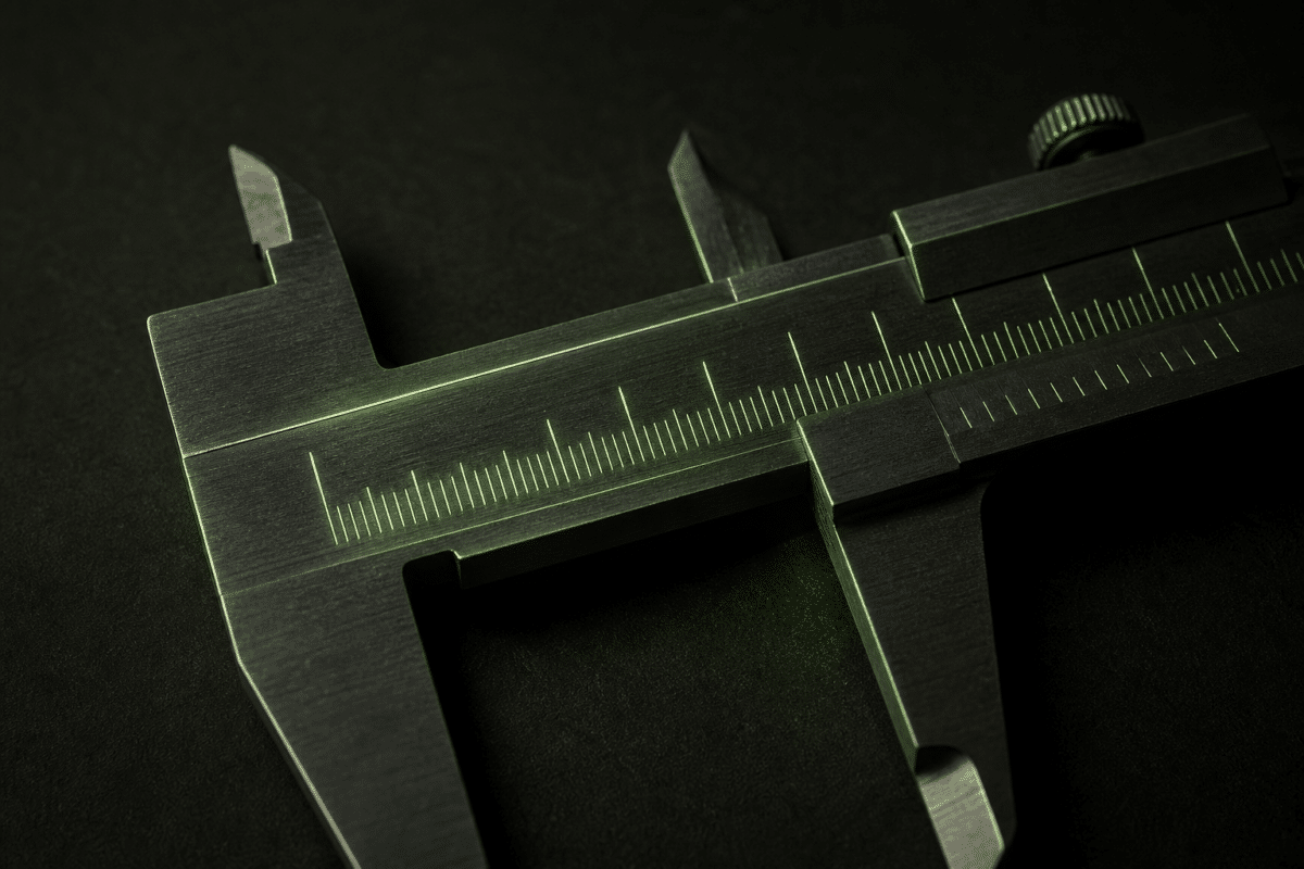 Close-up of a vernier caliper with scale markings on a dark surface.